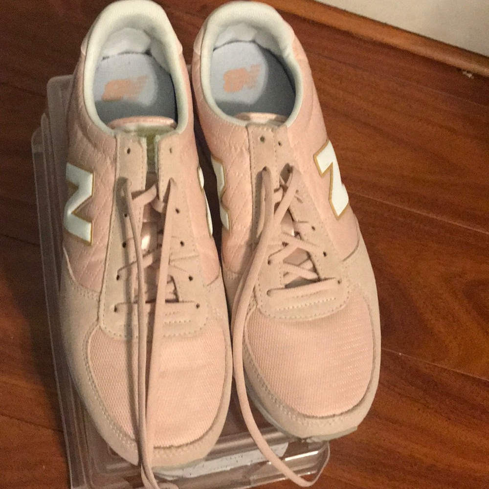 Pink New Balances with gold and white accents.